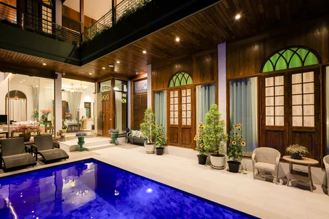Private pool courtyard at night with illuminated blue water, wooden ceiling and arched windows