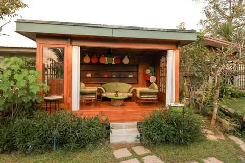 Open garden sala with rattan sofas, colourful pottery on shelves and tropical surroundings