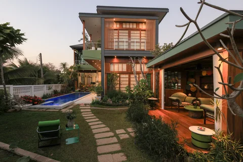 Villa exterior at dusk showing the full garden, pool, lit sala and two-storey facade
