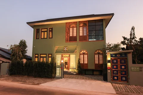 Villa front exterior at dusk - sage green two-storey facade with illuminated entrance and decorative mosaic gate