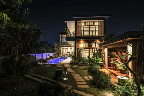 Villa exterior at night with glowing pool and the garden sala lit in the background