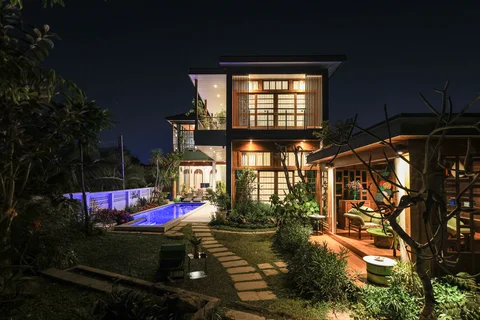 Villa at night from across the garden showing the pool and sala lit amid tropical greenery