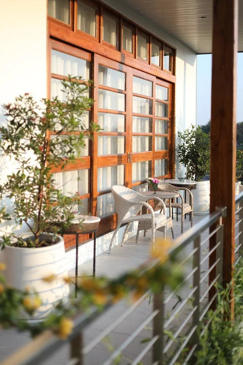 Upper floor balcony with wicker chairs, potted citrus trees and warm wooden folding doors