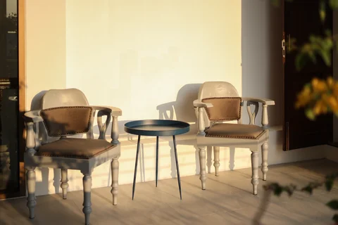 Corner terrace with two antique cream armchairs and a small side table bathed in afternoon sun