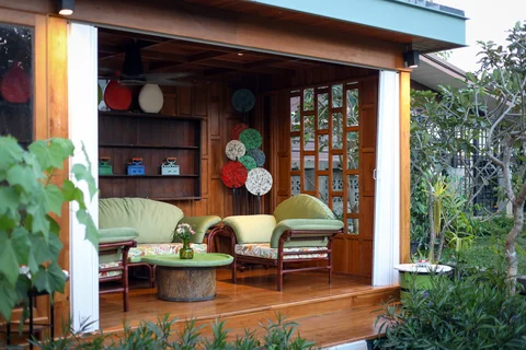 Garden sala with green rattan seating, hand-painted wall plates and tropical garden
