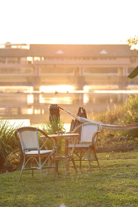 Riverside garden with two wicker chairs, small table and a hammock at golden hour