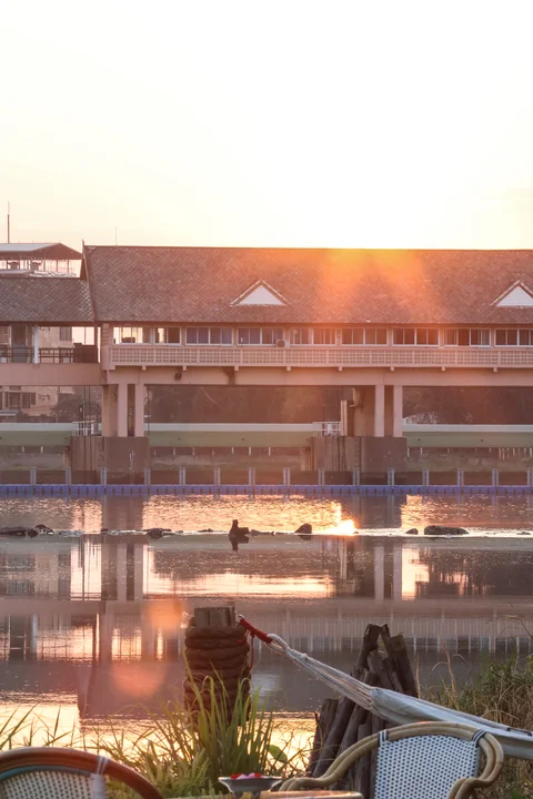 Golden sunrise over the river with warm reflections on the water, viewed from the villa garden